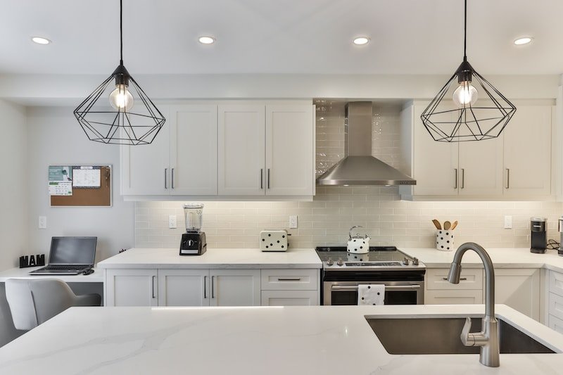 35 Savvy Kitchen Design Tricks to Maximize Your Space 4 white wooden kitchen cabinet with black pendant lamp